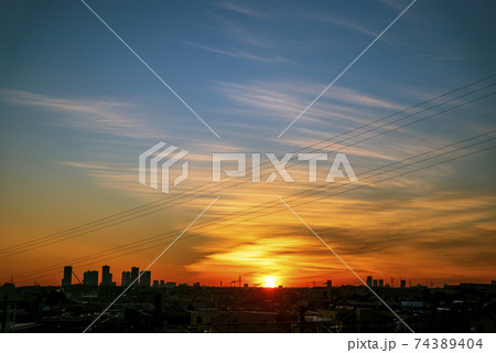 黄金色の太陽が地平線上に姿を現して雲をオレンジ色に輝かせる 74389404