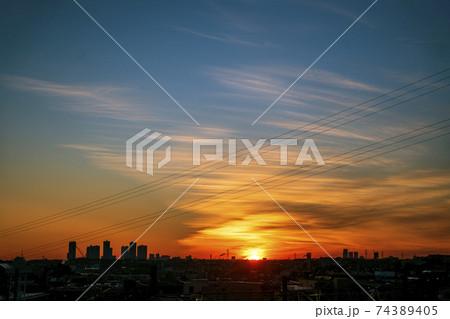 黄金色の太陽が地平線上に姿を現して雲をオレンジ色に輝かせる 74389405