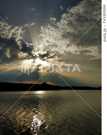 Natural landscape. Sunset over water, reflection of the sun and clouds in the water Natural landscape. Sunset over water, reflection of the sun and clouds in the water 74390999
