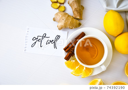 GET WELL - written on piece of paper among the products for the treatment of common cold - lemon, ginger, chamomile tea. Vitamin natural drink GET WELL - written on piece of paper among the products for the treatment of common cold - lemon, ginger, chamomile tea. Vitamin natural drink 74392190