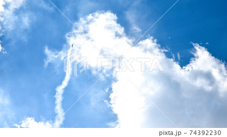 airplane doing acrobatics in blue sky leaves a smoke. Blue sky with airport contrail clouds. 74392230