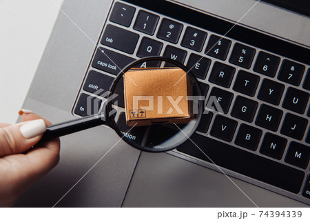 Cardboard box and a magnifying glass. Warehouse of finished products and equipment 74394339
