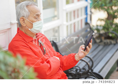 asian old elder senior man wearing face mask elderly using mobile smart phone cellphone. mature retirement lifestyle 74394823