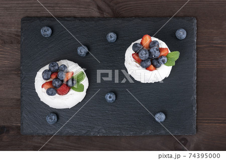 Cake Anna Pavlova. Airy meringue garnished with fresh strawberries and blueberries. Cake Anna Pavlova. Airy meringue garnished with fresh strawberries and blueberries. 74395000