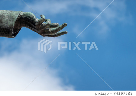 Hand of a bronze statue, open to show the will to peace. 74397535