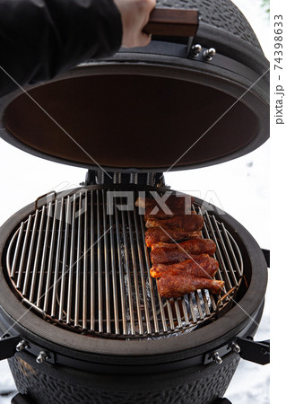 Winter bbq in the fresh white snow, Men grilling chicken wings in the winter onn grill Winter bbq in the fresh white snow, Men grilling chicken wings in the winter onn grill 74398633