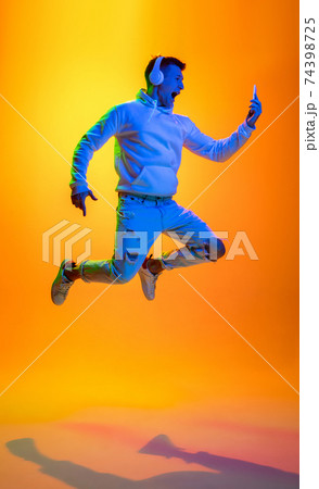 Caucasian beautiful man's portrait isolated on yellow studio background in multicolored neon light Caucasian beautiful man's portrait isolated on yellow studio background in multicolored neon light 74398725