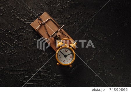 Yellow alarm clock in a mousetrap, time trap concept Yellow alarm clock in a mousetrap, time trap concept 74399866