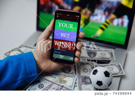 Lucky winner at football betting with phone in hand and dollar bills. Betting and gambling concept Lucky winner at football betting with phone in hand and dollar bills. Betting and gambling concept 74399944