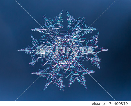 Snowflake on smooth gradient background. Macro photo of real snow crystal on glass surface. This is small snowflake with unusual pattern. 74400359