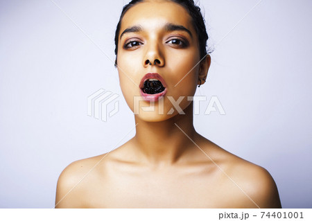 young pretty indian woman with dry fruit in mouth on white background young pretty indian woman with dry fruit in mouth on white background 74401001
