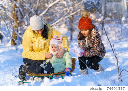 family posing in the winter forest, mother and children, bright sunlight and shadows on the snow, beautiful nature 74401557