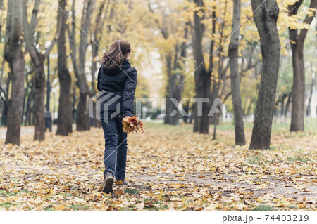 a girl running through the park and enjoys autumn, beautiful nature with yellow leaves 74403219