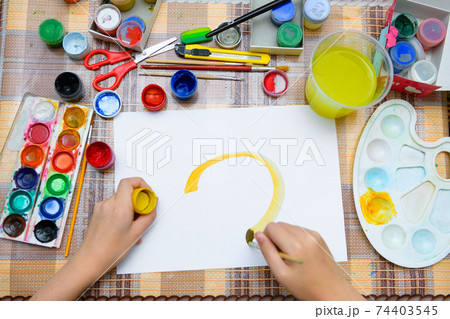 a girl drawing watercolor a big smiling sun on a blank white paper, artistic creation at home, makes creative artwork 74403545