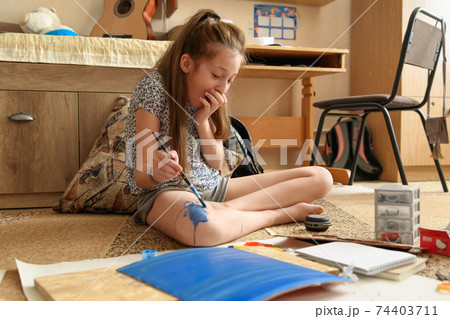 girl draws at home, artistic creation, makes creative artwork from paper, paints and brushes girl draws at home, artistic creation, makes creative artwork from paper, paints and brushes 74403711