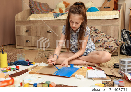 girl draws at home, artistic creation, makes creative artwork from paper, paints and brushes girl draws at home, artistic creation, makes creative artwork from paper, paints and brushes 74403731