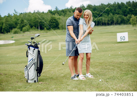 Beautiful couple playing golf on a golf course Beautiful couple playing golf on a golf course 74403851