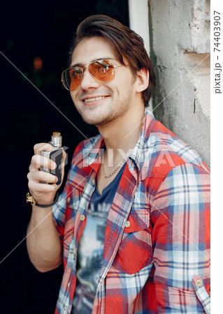 Stylish and elegant man in a city with vape 74403907