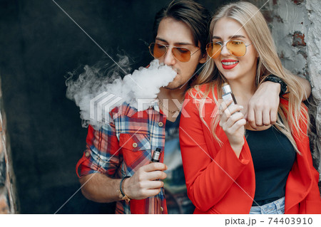 Stylish young couple with vape in a city 74403910