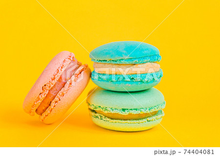 Sweet almond colorful unicorn blue pink macaron or macaroon dessert cake isolated on trendy yellow modern fashion background. French sweet cookie. Minimal food bakery concept Copy space Sweet almond colorful unicorn blue pink macaron or macaroon dessert cake isolated on trendy yellow modern fashion background. French sweet cookie. Minimal food bakery concept Copy space 74404081