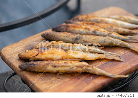 Crispy breaded european smelt fish on wooden cutting board at food festival Crispy breaded european smelt fish on wooden cutting board at food festival 74407511