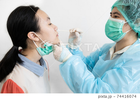 Asian nurse in protective suite taking a swab for nasal mucus test sample from child girl patient,medical examination COVID-19 testing,checking,diagnosis of Coronavirus from an infected schoolgirl 74416074