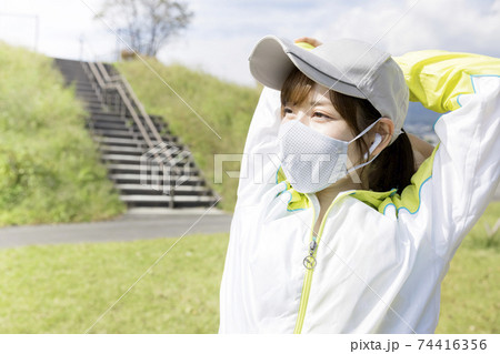 マスクを着用して深呼吸をするトレーニングウェア姿の若い女性 74416356