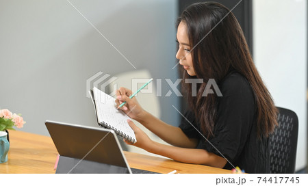 The tutor is tutoring by making video calls with students at a wooden desk. 74417745