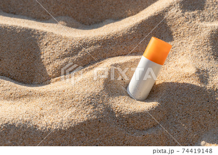 Bottle of sunscreen lotion on the beach by the sea 74419148