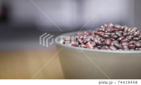 A bowl of red beans on a table on a blurred background of a window 74419448