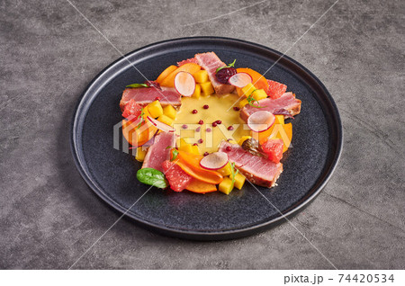 Tuna steak salad, mango sauce, herbs and spices on a dark plate Tuna steak salad, mango sauce, herbs and spices on a dark plate 74420534