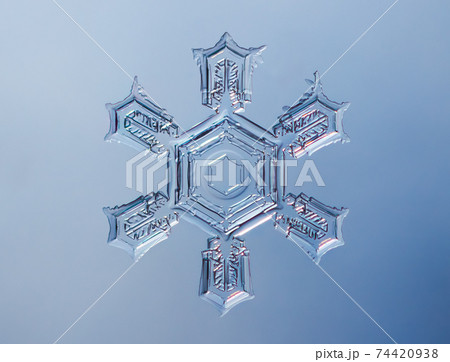 Snowflake on smooth gradient background. Macro photo of real snow crystal on glass surface. This is small snowflake with unusual pattern. 74420938