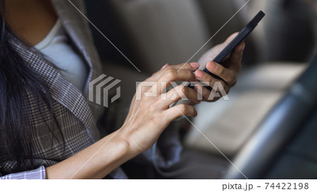 Female using smartphone in her hands in her car while stuck at the traffic light Female using smartphone in her hands in her car while stuck at the traffic light 74422198