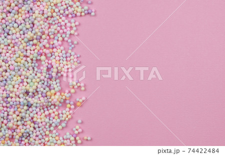 Small colorful pastel balls in a border on pink paper 74422484