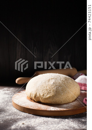 Homemade wholemeal rye wheat dough for bread on wooden table with flour, rolling-pin, dark rustic background. Homemade wholemeal rye wheat dough for bread on wooden table with flour, rolling-pin, dark rustic background. 74423151