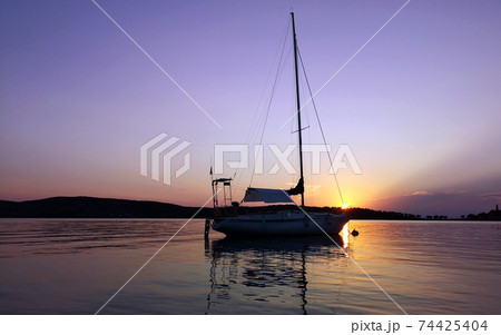 A sailboat anchored in a bay  on sunset 74425404