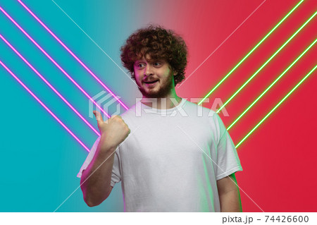 Caucasian man's portrait isolated on gradient blue-red studio background in neon light with glowing lines. Concept of human emotions, facial expression, sales, ad. 74426600