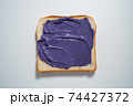spreading Purple paste on a toast on white Background. Top view 74427372