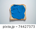 spreading Dark Blue paste on a toast on white Background. Top view 74427373