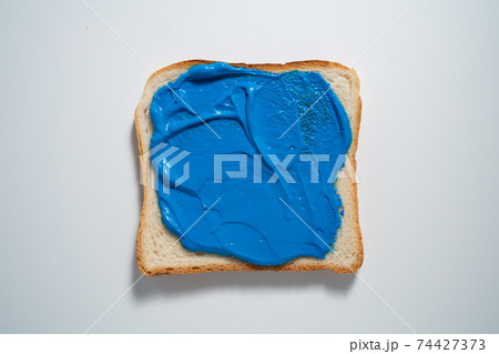 spreading Dark Blue paste on a toast on white Background. Top view 74427373