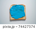 spreading Blue paste on a toast on white Background. Top view 74427374