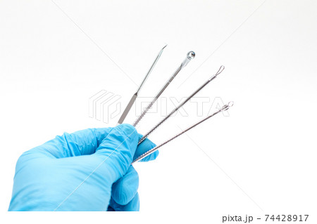 Doctor's hand in a blue glove holds Acne removal tools Doctor's hand in a blue glove holds Acne removal tools 74428917