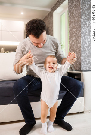 Father teaching a baby to walk in living room at home 74430648