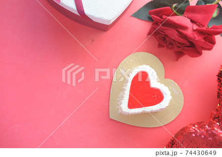 Top view of heart shape cake, gift box, and rose flower on red background  74430649