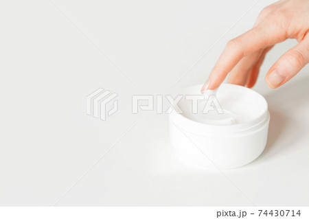 Closeup shot of female hand touching moisturizer cream. White jar of skin cream. Isolated on white 74430714