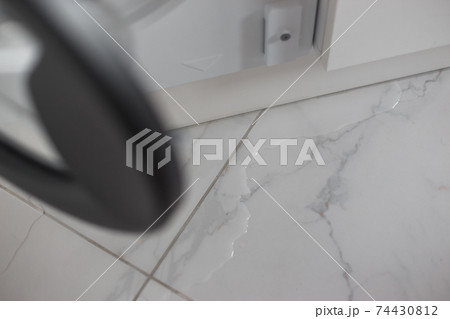 Spilled water leaked from washing machine built into the kitchen furniture. Spilled water on the tiled floor, flooding. 74430812