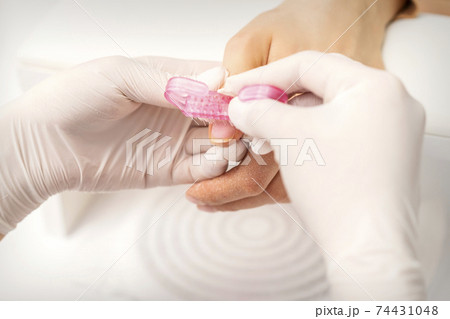 Manicurist brushing dust from nails 74431048