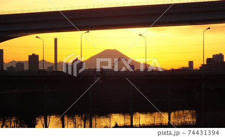 足立区と荒川区を繋ぐ扇大橋を渡る舎人線と富士山と荒川遊園地の観覧車の観える冬の夕暮れの風景 の写真素材