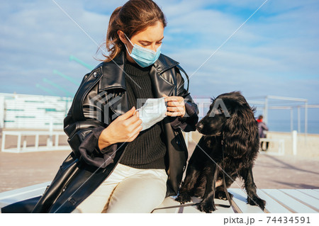 Young woman in medical mask puts on protective mask Young woman in medical mask puts on protective mask 74434591