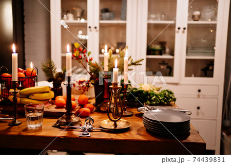 Low light. tangerines and apples in a metal basket and burning candles Low light. tangerines and apples in a metal basket and burning candles 74439831